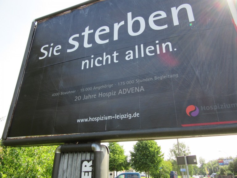 A billboard currently displayed in Leipzig-Engelsdorf, reading: You DIE – not alone. What sounds like an advertisement for death itself is one for a Leipzig hospice. (Photo: Maximilian Georg)