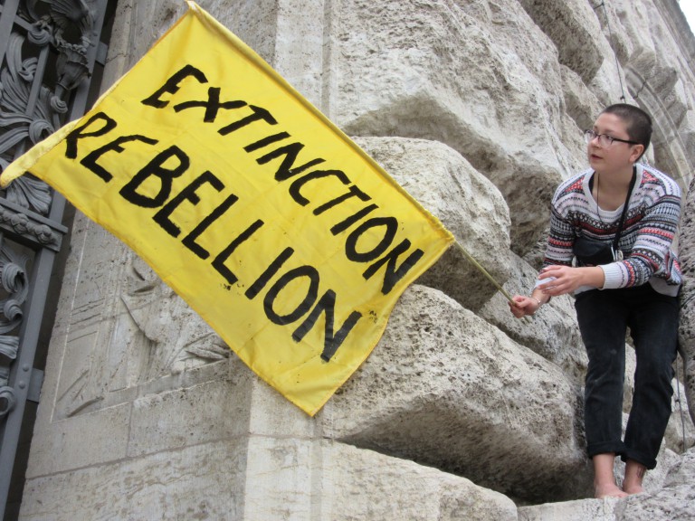 Perched on the side of Leipzig's Neues Rathaus, a member of Extinction Rebellion waves a flag. 