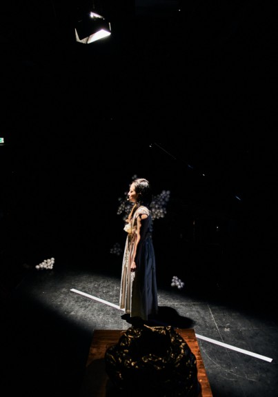 Woman standing in spotlight on stage