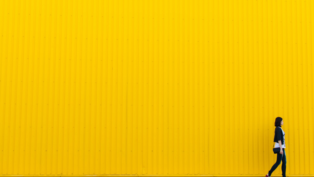 Woman walking against yellow background