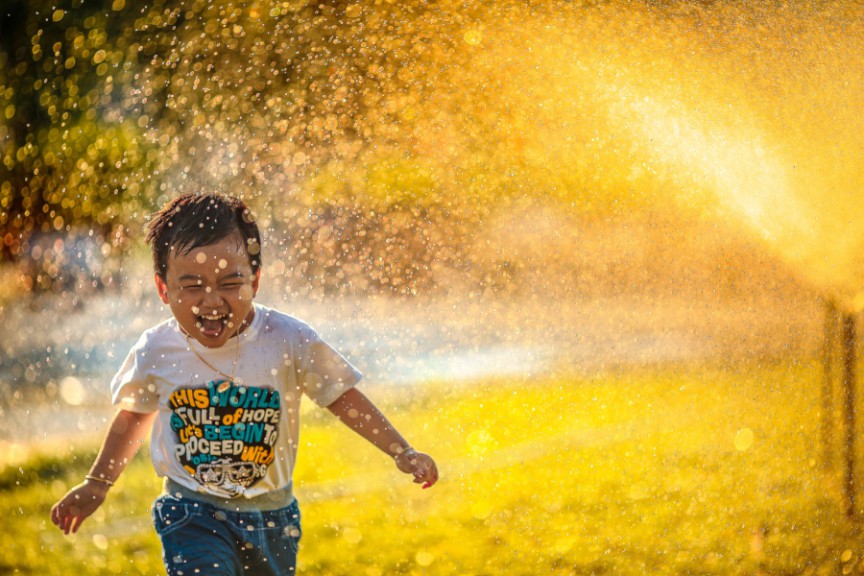 toddler running through sprinkler