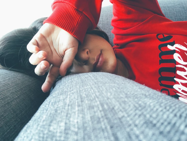 woman lying on couch with face covered