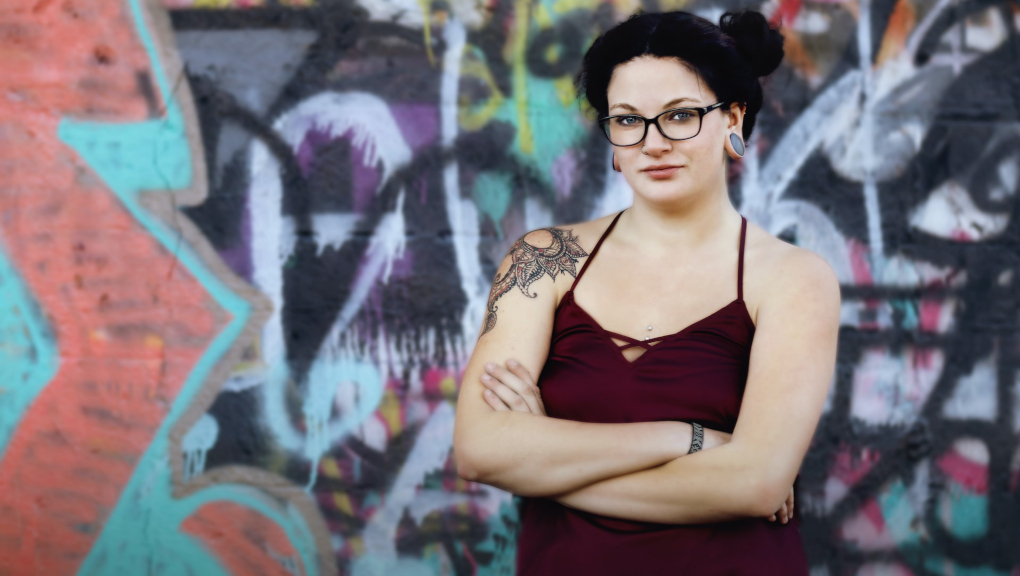 Woman with tattoos in front of graffiti