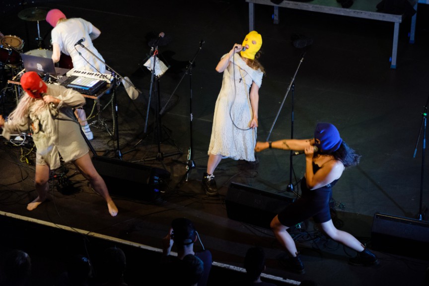 Four female performers in masks on stage