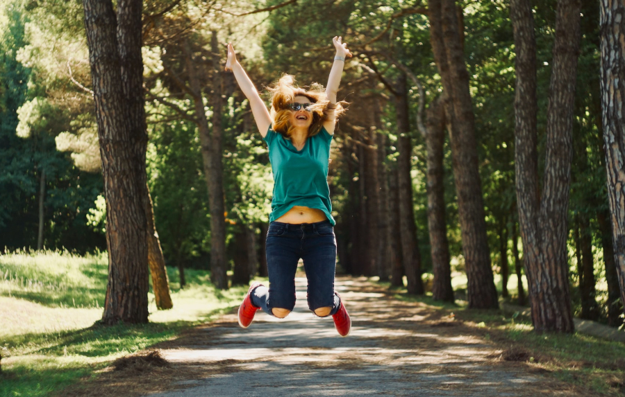 Woman jumping in forest path