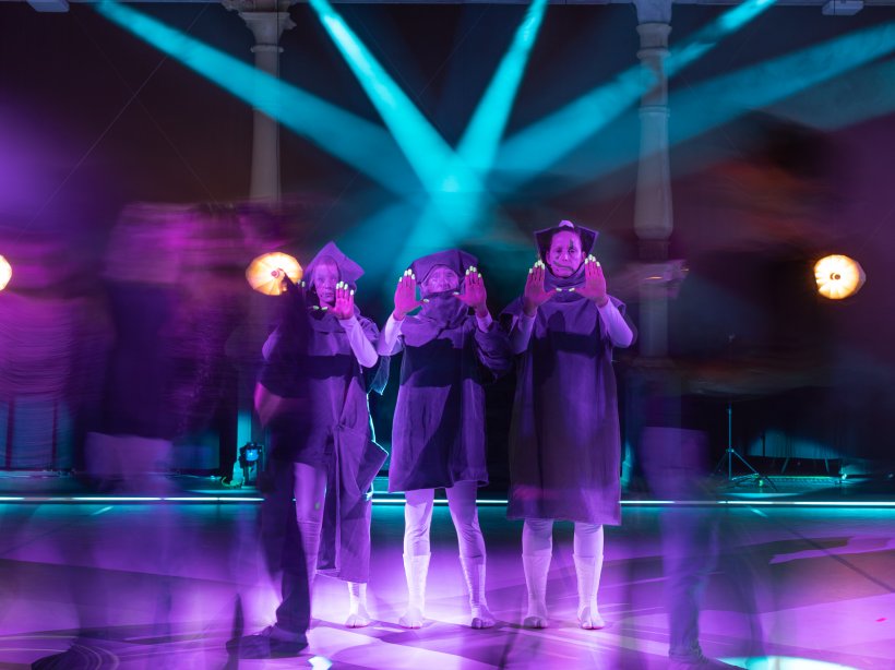 three female performers on stage under blue light