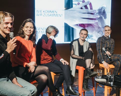 Panel of speakers seated on stage