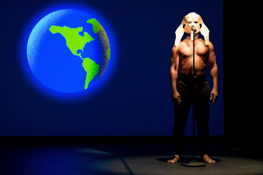 Bare-chested man in traditional mask next to globe