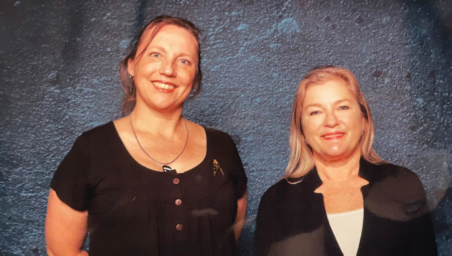 two women facing camera smiling