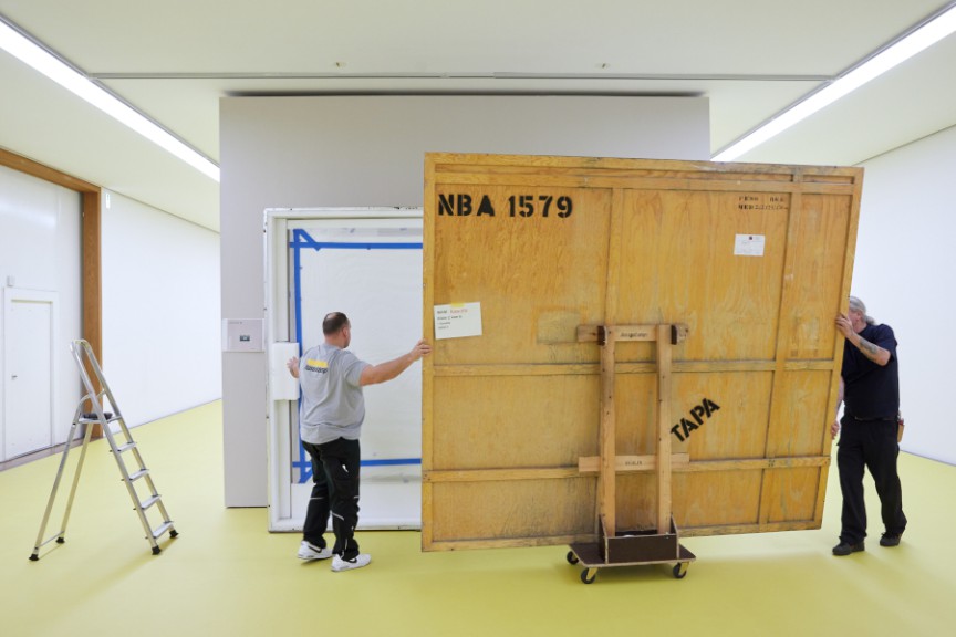 Two men moving large painting in museum