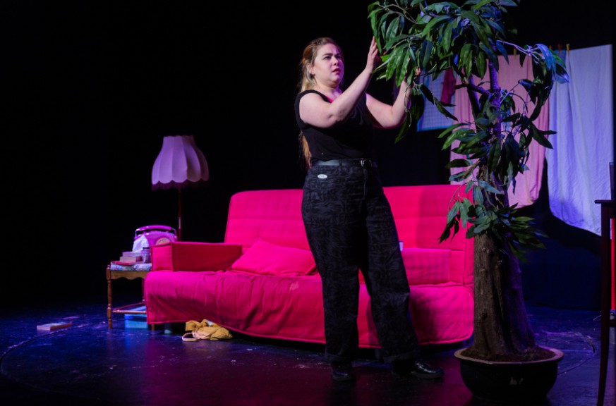 woman tending to plant on stage in front of pink couch