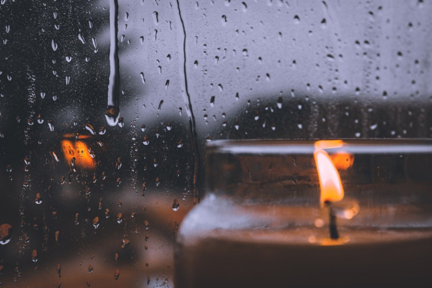 candle against rain-spattered window