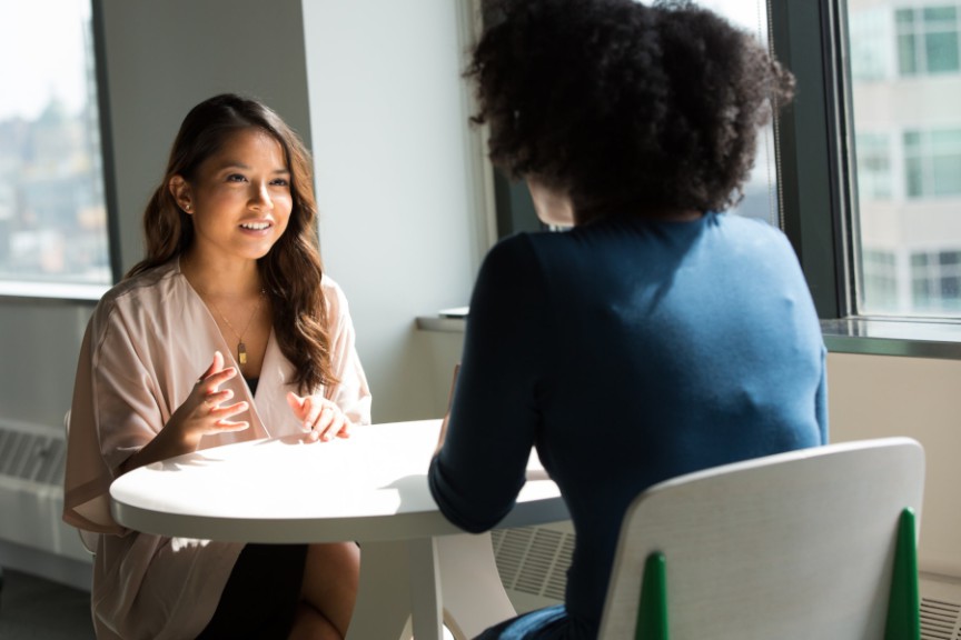 two women seated at small table talking