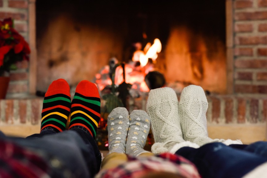 three pairs of stockinged feet in front of fireplace