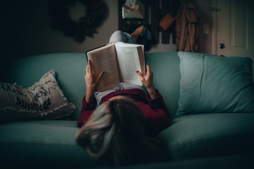 woman lying on couch reading